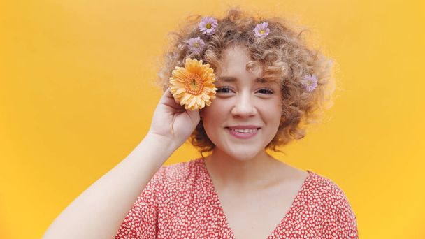 Cute Girl Posing With Orange Gerbera Daisy Flower Over Bright Yellow Background - Photo, Image