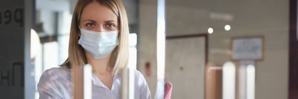 Frau in medizinischer Schutzmaske öffnet Tür - Foto, Bild