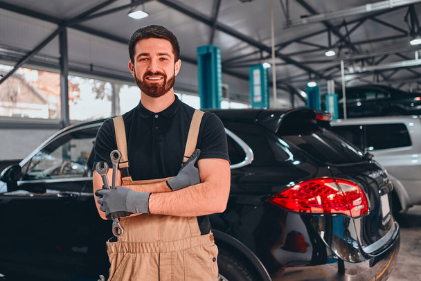 Feliz hombre mecánico sonriente en el taller. Servicio de coches, reparación, mantenimiento y concepto de personas. Vista frontal. - Foto, imagen