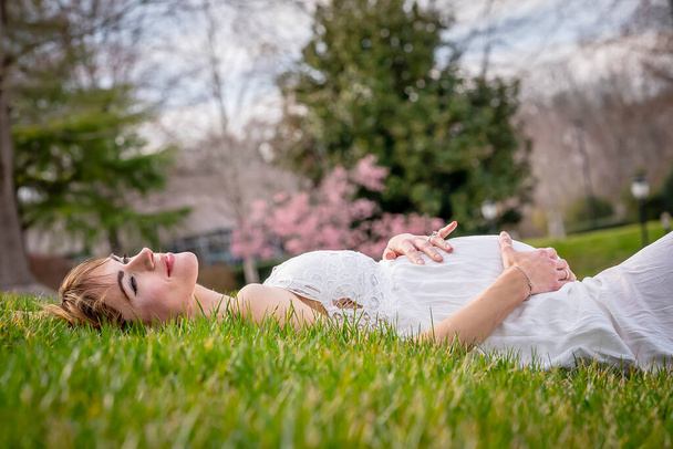 A beautiful expectant mother poses in an outdoor environment - Фото, изображение