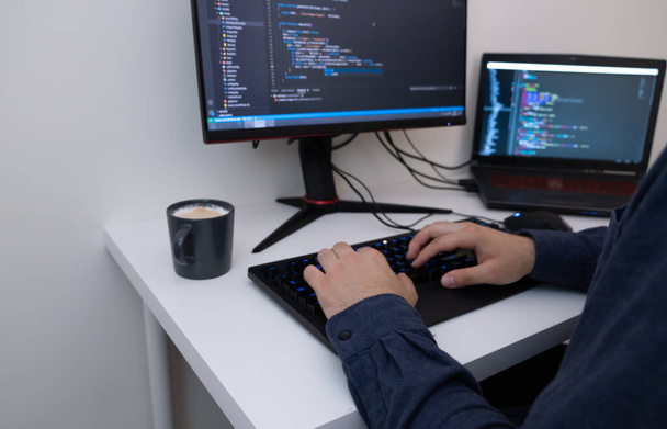 Programador masculino trabajando desde casa. Las manos masculinas están escribiendo el código. Concepto de tecnología y tarea. - Foto, imagen