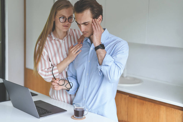 Young couple standing on the kitchen with laptop and working from home - Photo, Image