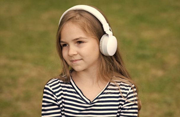 Cute little kid listen to audio language course in headphones outdoors, english - Фото, зображення