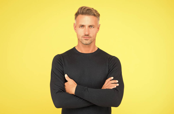 handsome confident man crossed hands has stylish hairdo and groomed face bristle on yellow background, mens beauty - Foto, Imagem
