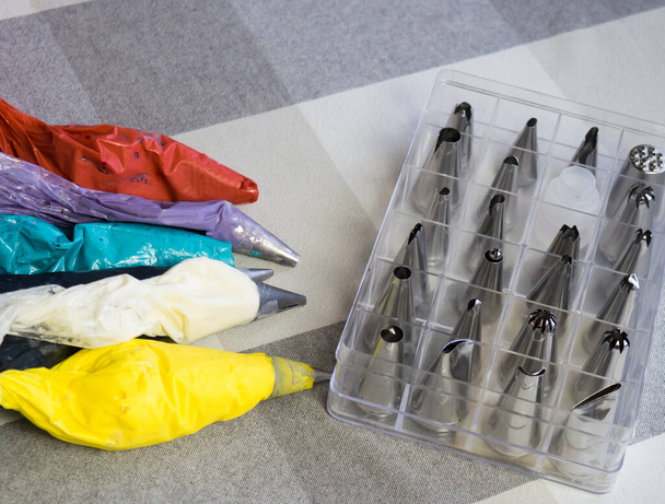 tašky na pečivo s pestrobarevnou smetanou a tryskami leží na stole - Fotografie, Obrázek