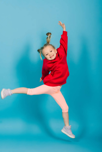 Portret wesołej dziewczyny skaczącej i tańczącej na tle studia - Zdjęcie, obraz