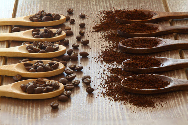 Chicchi di caffè e caffè macinato in cucchiai di legno su sfondo marrone - Foto, immagini