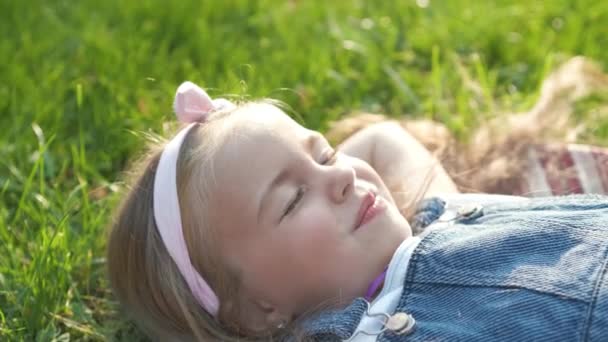 Menina bonita criança deitado na grama verde no verão tirar uma soneca. - Filmagem, Vídeo