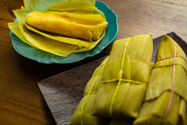 Une portion de pamonhas attachée à la balle de maïs et un pamonha ouvert sur l'assiette, prêt à être consommé. Pamonha est un aliment typiquement brésilien, fait avec de la pâte de maïs vert. - Photo, image