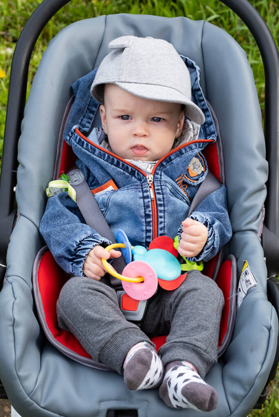 Little boy sitting in a stroller on a walk in the park - Foto, Bild