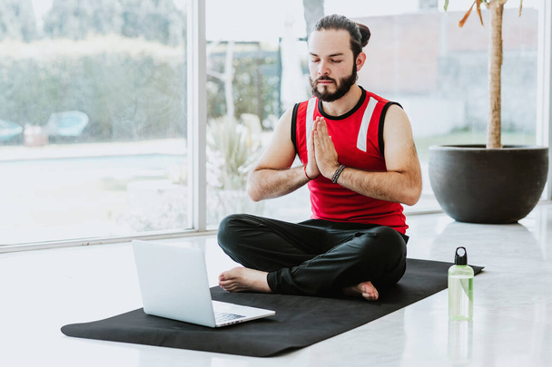 Latynos medytuje z zamkniętymi oczami słuchając instruktora jogi online w domu w Meksyku - Zdjęcie, obraz