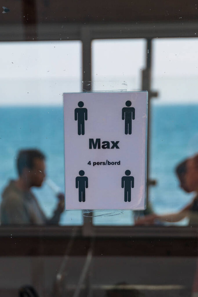 Kaseberga, Svezia Una finestra del ristorante con un adesivo che dice max 4 persone per tavolo in svedese. - Foto, immagini