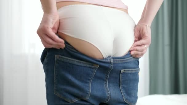 Primo piano di giovane donna obesa tirando jeans stretti sul grande fondo. Concetto di sovrappeso, obesità femminile, problemi di dieta e sovrappeso - Filmati, video