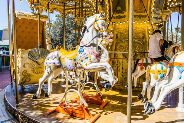 Párizs-stílusú körhinta a lovakkal az előtérben. Szórakoztató koncepció gyerekeknek - Fotó, kép