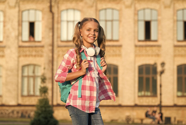 Sunny morning at school yard. Happy carefree child. School classes. Little girl with backpack. School life. Student. Modern education. Cheerful teen listening music. Schoolgirl going to school - Photo, image