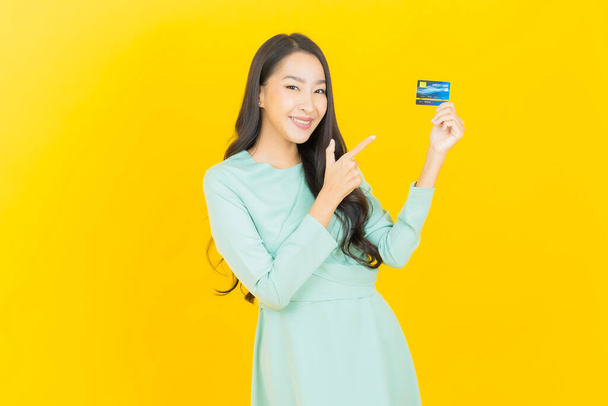 Портрет красива молода азіатка посміхається з кредитною карткою на кольоровому фоні
 - Фото, зображення