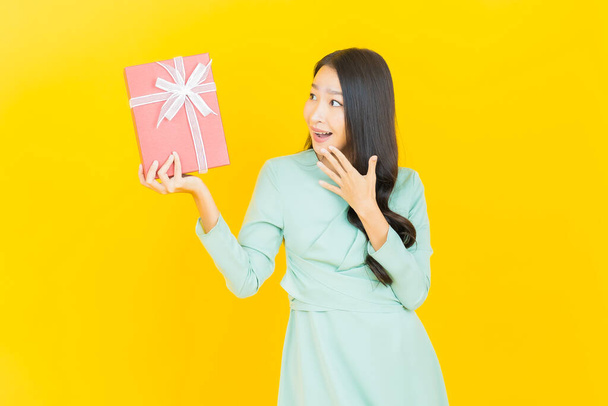 Portrait beautiful young asian woman smile with red gift box on color background - Foto, Imagem
