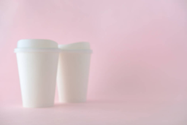 verschwommen von weißem Papier Kaffeetasse auf rosa Hintergrund, defokussieren Konzept für Produkt-Hintergrund. - Foto, Bild