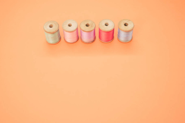 A colorful sewing threads isolated on a pastel orange background with free space for text - Photo, Image