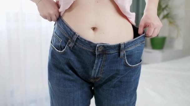 Красивая стройная женщина с большими джинсами в зеркале. Концепция диеты, похудения и здорового образа жизни. - Кадры, видео