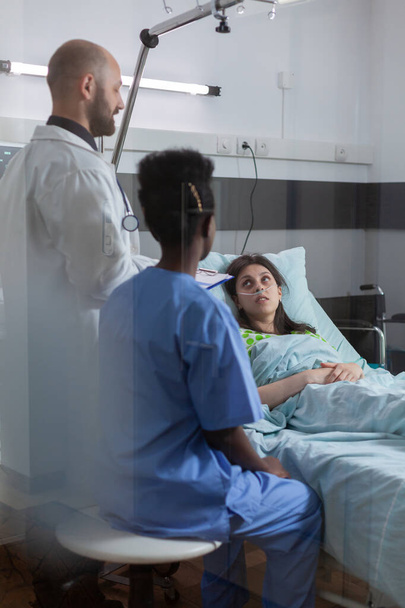 Medizinisches Team überwacht kranke Frau, die Krankheitssymptom erklärt - Foto, Bild