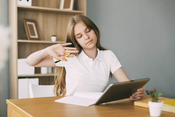Дівчина-підліток робить домашнє завдання зі своїми друзями за допомогою відеозв'язку за допомогою планшета
 - Фото, зображення