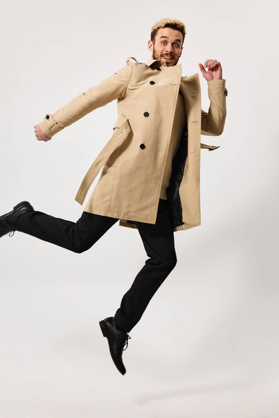 людина в бежевому пальто осінній стиль стрибок студії світлого фону
 - Фото, зображення