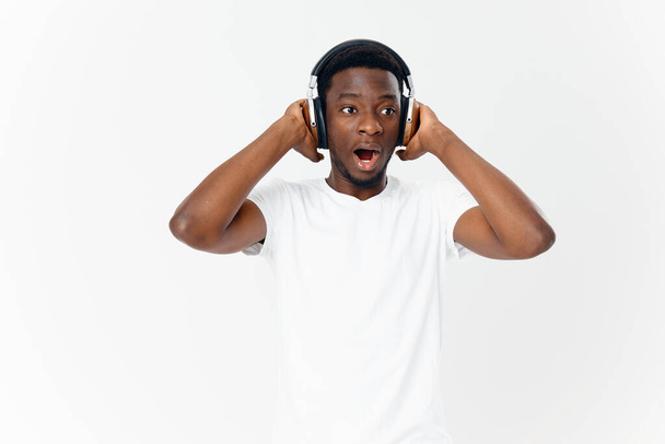 mies afrikkalainen ulkonäkö kuulokkeet valkoinen t-paita kuuntelee musiikkia viihdettä - Valokuva, kuva