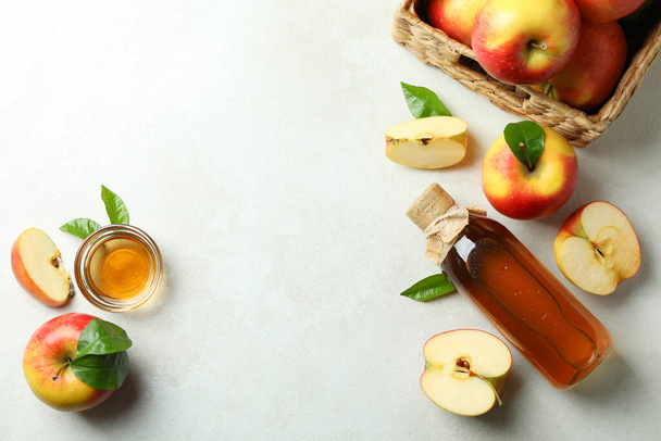 Zelfgemaakte appelazijn en ingrediënten op witte getextureerde tafel - Foto, afbeelding