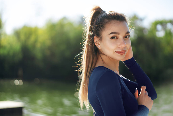 Portrait of a young smiling woman wearing sportswear in morning park - Photo, Image