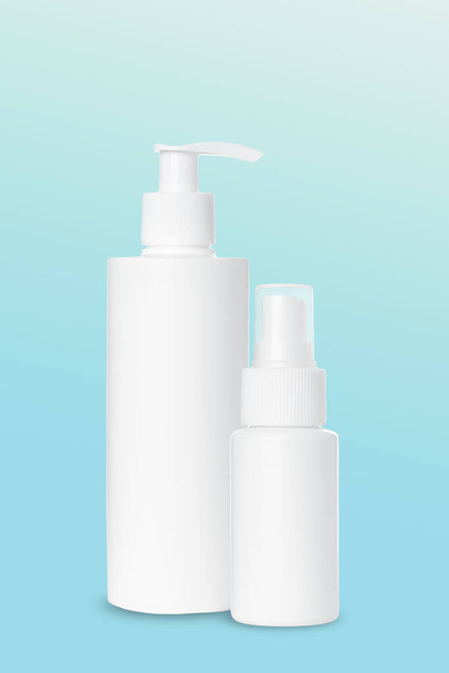 tyhjä valkoinen muovi isku ja spray pullot kosmetiikka sinisellä pohjalla. Matkijat - Valokuva, kuva