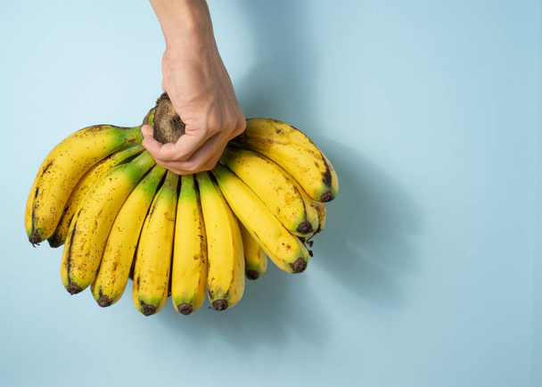 Ein Mann hält ein Bündel Bananen mit einem Kopierplatz. - Foto, Bild