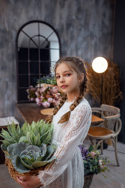 Ein nettes kleines Mädchen in einem schönen Kleid zu Hause. Prinzessin mit langen wallenden Haaren mit Blumen im Retro-Pastellkleid. pflegt die Pflanzen - Foto, Bild