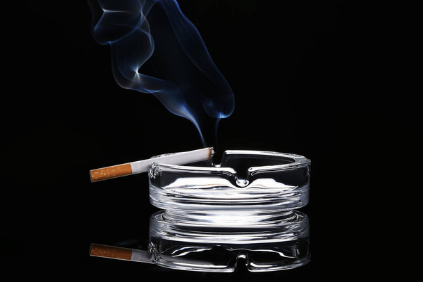 Cigarette and ash tray on dark background - Photo, Image
