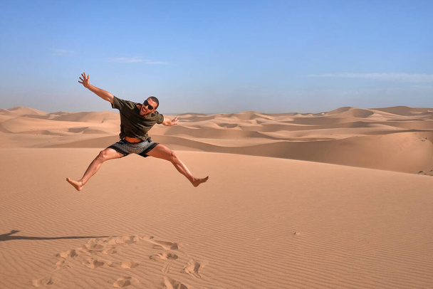 ευτυχισμένος άνθρωπος άλμα για διασκέδαση απολαμβάνοντας έρημο ταξίδια περιπέτειας - Φωτογραφία, εικόνα