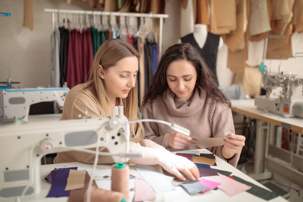 Κοντινό πλάνο του γυναικείου στυλίστας μόδας και του πελάτη κρατώντας δείγματα χρωμάτων των υφασμάτων επιλέγοντας το σχέδιο για το νέο φόρεμα, αντιγραφή χώρου - Φωτογραφία, εικόνα