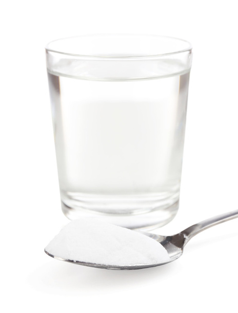 κουταλάκι σόδα πάνω από το ποτήρι του νερού, που απομονώνονται σε λευκό - Φωτογραφία, εικόνα