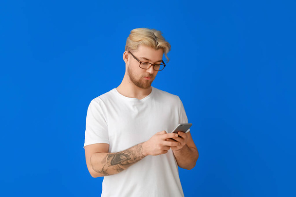 Handsome man using mobile phone on color background - Фото, изображение