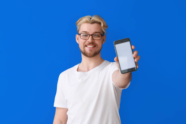Knappe man met mobiele telefoon op kleur achtergrond - Foto, afbeelding