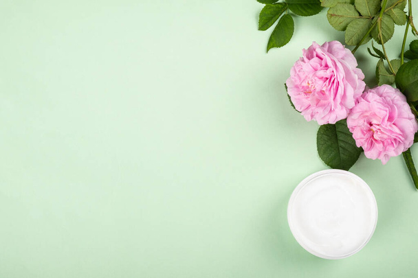 cosmetic cream with rose scent,beauty skin care flat lay with copy space on a green background - Photo, Image