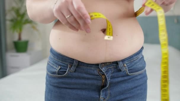 Closeup of young woman with fat belly measuring her waistline. - Footage, Video