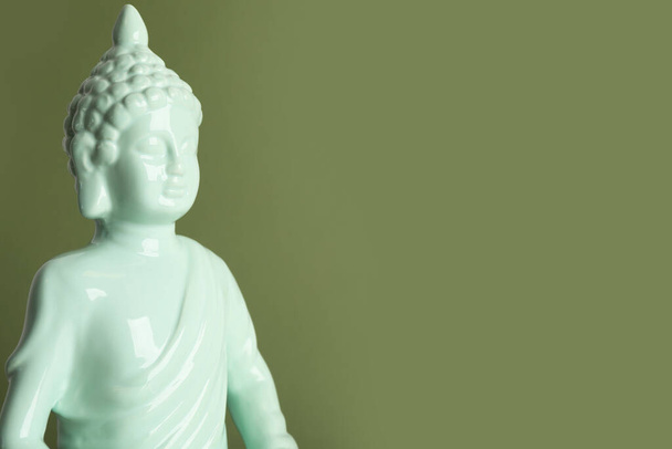 Beautiful ceramic Buddha sculpture on green background. Space for text - Foto, Bild