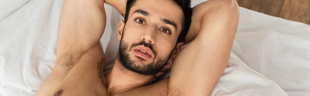 Top view of shirtless man lying on bed and looking at camera, banner  - Foto, immagini