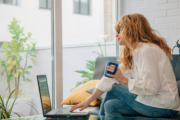 Frau zu Hause mit Computer und Tasse Kaffee - Foto, Bild
