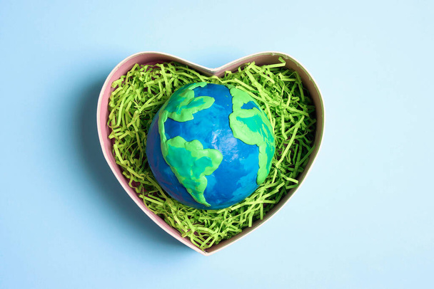 Planet in a heart gift box on a blue background. Earth Day, ecology and nature protect. - Foto, immagini