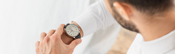 Vista recortada del hombre de negocios borroso mirando el reloj de pulsera, pancarta  - Foto, imagen