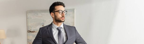 Businessman in eyeglasses and suit looking away at home, banner  - Foto, imagen