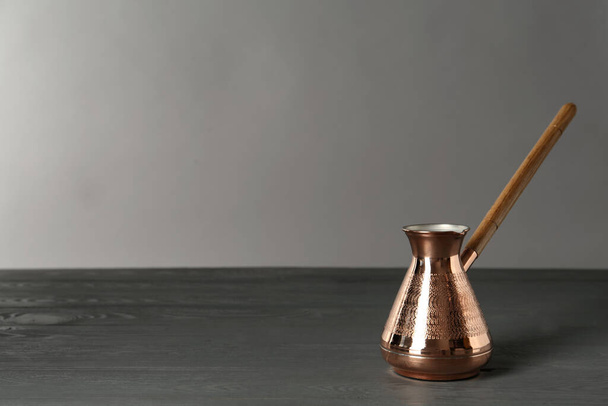 Cafetera turca de cobre sobre mesa de madera gris, espacio para texto - Foto, imagen
