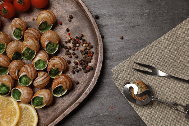 Delicious cooked snails served on grey table, flat lay - Foto, Imagem