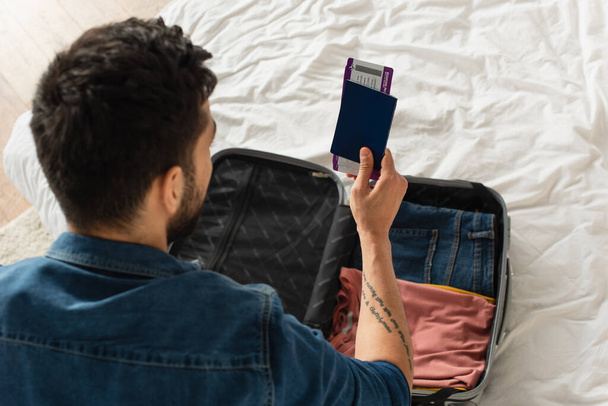 Visão geral do homem detentor de passaporte com passagens aéreas perto da mala em casa  - Foto, Imagem